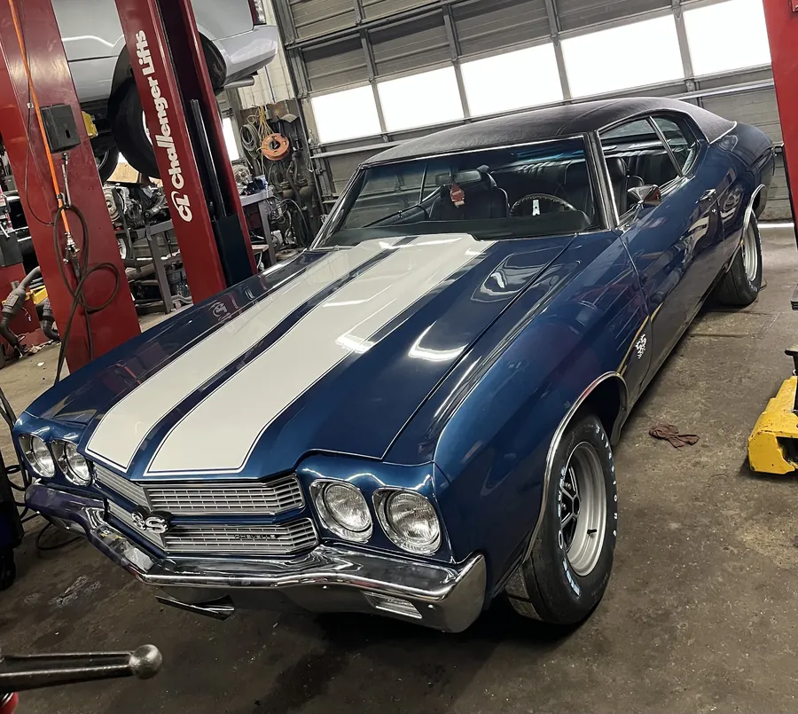 A blue Chevelle SS with white stripes in the service bay