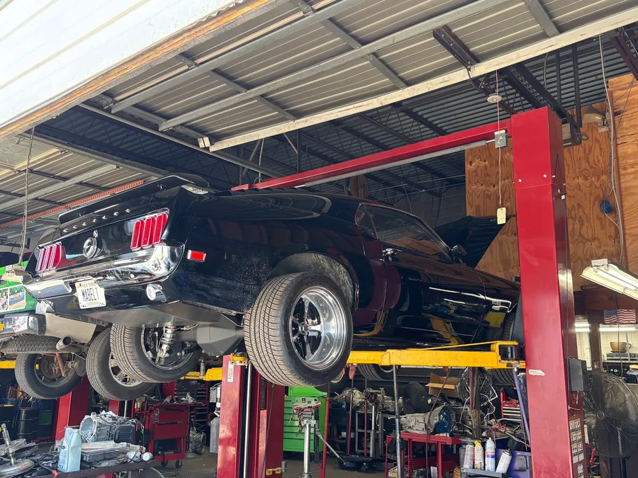 A black classic Mustang raised on the lift in the shop