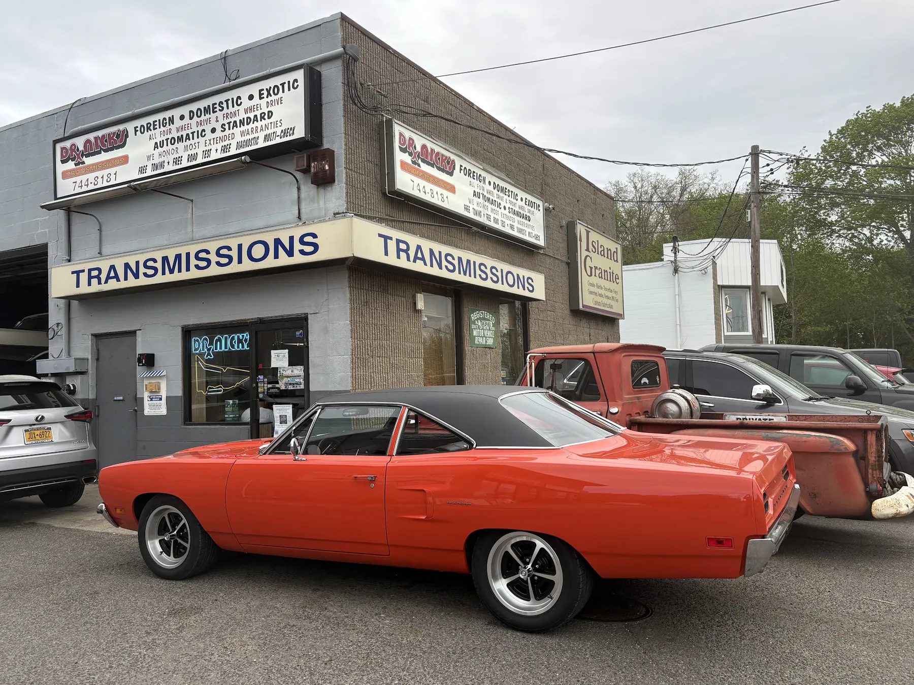 A restored orange Plymouth Road Runner parked outside Dr. Nick's Transmissions on Route 25A